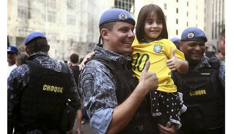 Policial com criança em protesto no Brasil